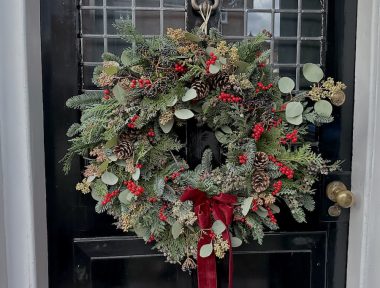 Jingle Bells Christmas Wreath against a black door.