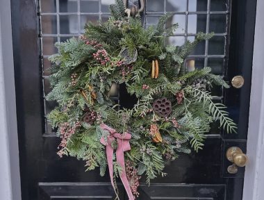 Silent night christmas wreath hung on a black door.